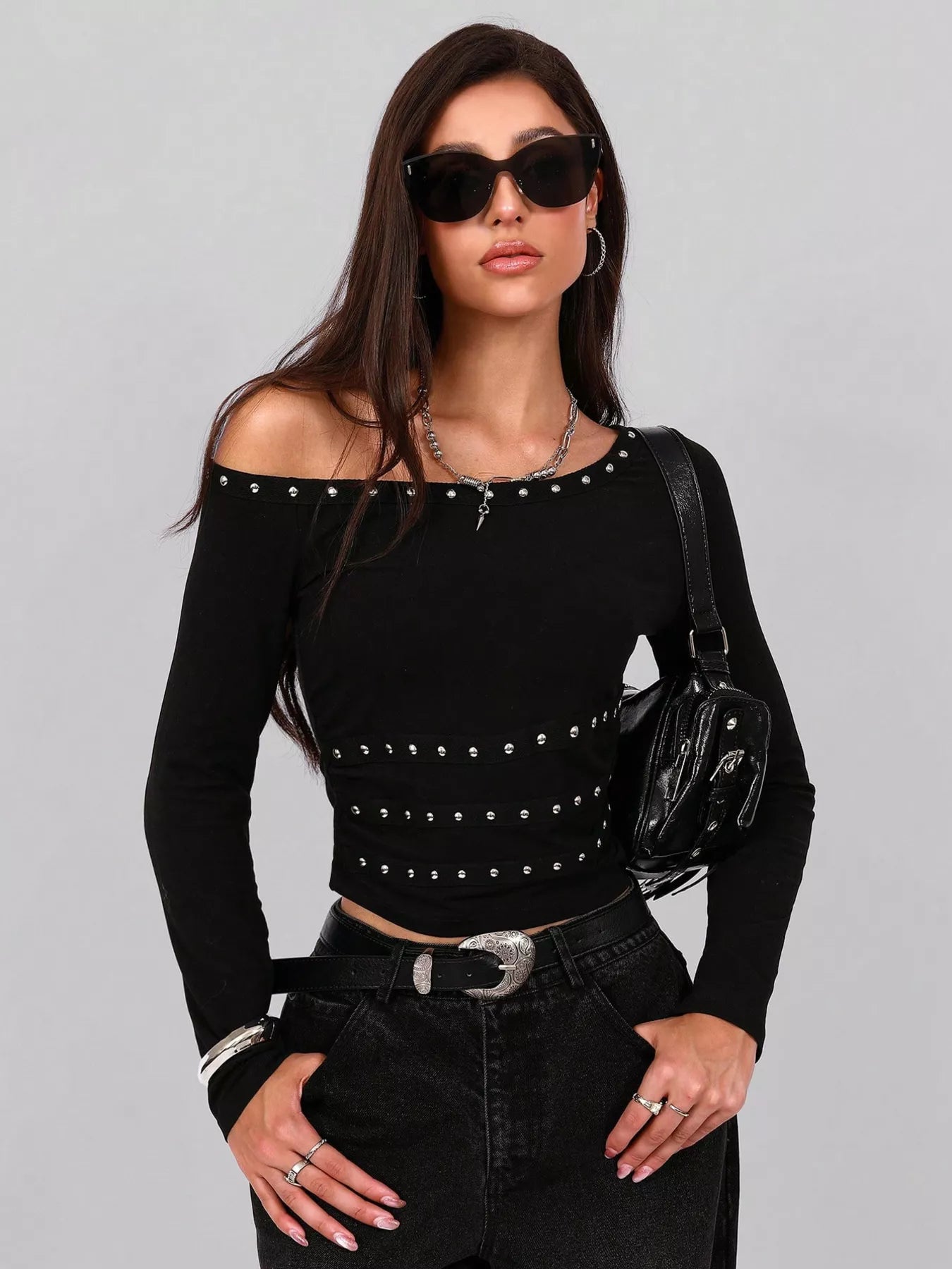 Woman wearing a black off-shoulder top with studs and black pants