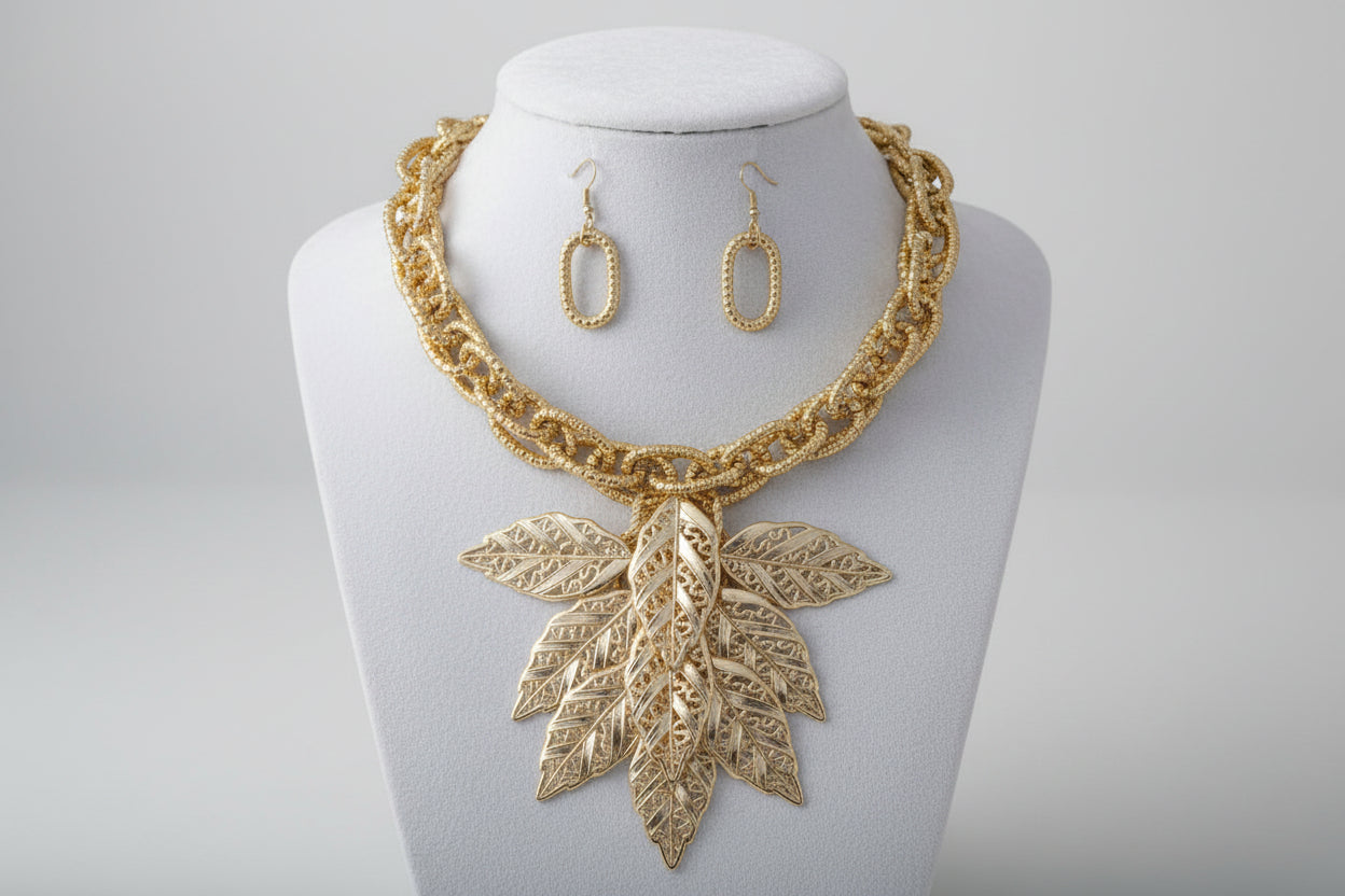 Women's Bib Necklace Set. Autumn-inspired Fall Seasonal Statement Necklace. Chunky Lightweight Gold Metal Twist Design Oval Double Link Chain Necklace Featuring Bib Comprised of High-Shine Polished Gold Acrylic Layered Filigree Leaf Drop Details.