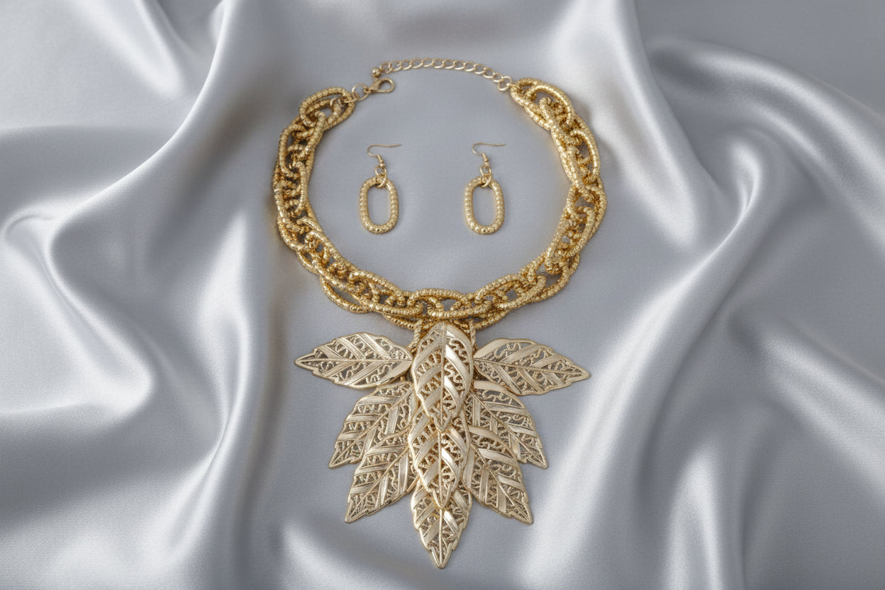 Women's Bib Necklace Set. Autumn-inspired Fall Seasonal Statement Necklace. Chunky Lightweight Gold Metal Twist Design Oval Double Link Chain Necklace Featuring Bib Comprised of High-Shine Polished Gold Acrylic Layered Filigree Leaf Drop Details. 