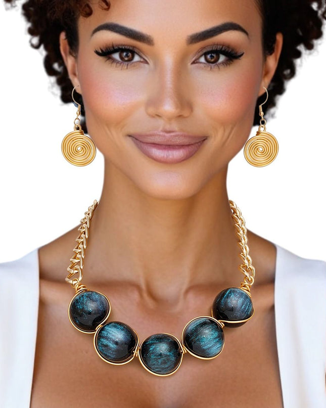 Women's Collar Necklace Set. Glossy and Galactic Chunky Gold Metal Chain Necklace with Eye-catching Centerpiece Collar Comprised of Jumbo Black Resin Ball Beads Featuring Swirled Blue Glitter Inlay and Hand-wrapped Gold Metal Wire Detail. 