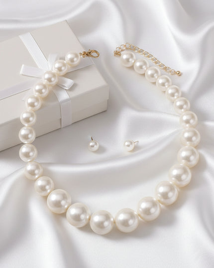 Women's Pearl Necklace Set. Timeless Silhouette Glossy Graduated Cream Acrylic Pearl Necklace. Single Strand Chunky Design. Pearls Measure 18mm to 24mm. Gold Metal Lobster Clasp Closure. Includes Matching Pearl Stud Post Backing Earrings.
