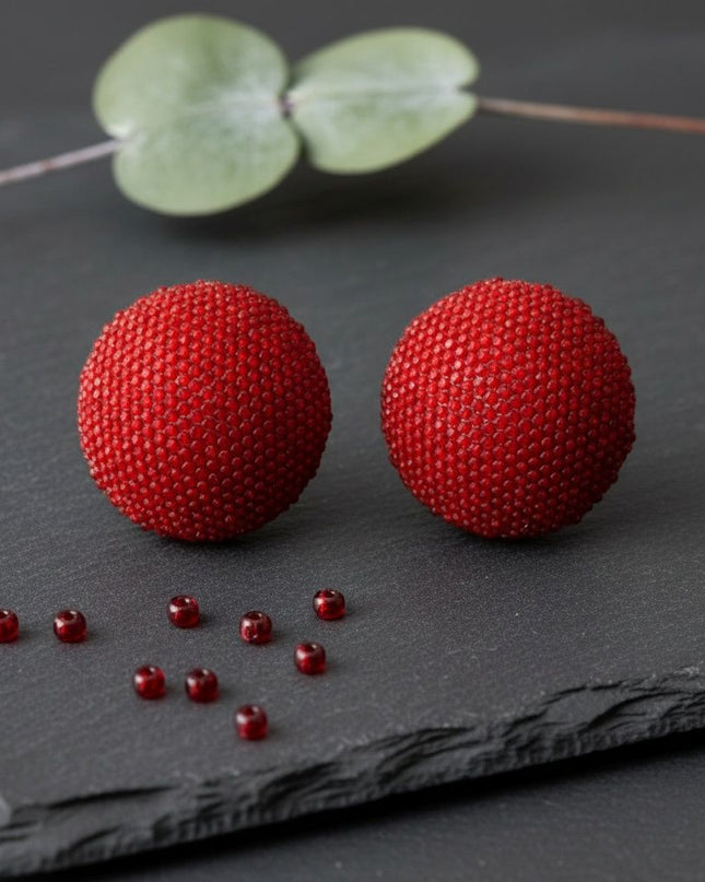 Women's Clip-On Earrings. Maximum Sparkle Statement Earrings. Bold Hollow Gold Metal Oversized Domed Clip-On Earrings Encrusted with Shimmering Red Rhinestones. Dome Measures .5 inches tall. Paddle Back Closure.
