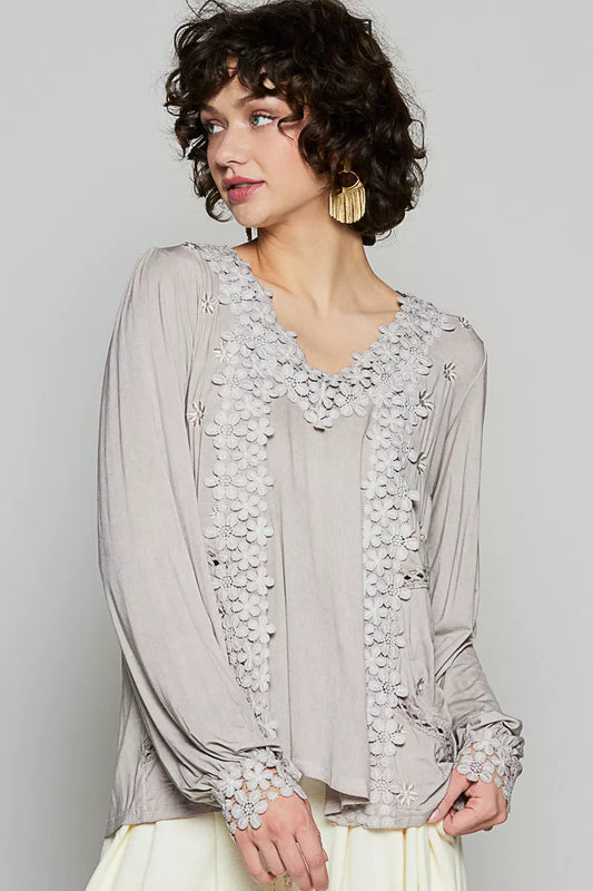The Floral Embroidery Woven Top offers a relaxed fit and delicate floral lace trim along the low V neckline. Floral embroidery detailing on the side front adds a charming touch to the design. The back features see-through lace shirring below the yoke to provide a roomy fit. This top is elegantly finished with clean hems for a polished look. Complete with shirred long sleeves and scallop floral trim with side button closure, this top exudes feminine charm and sophistication.