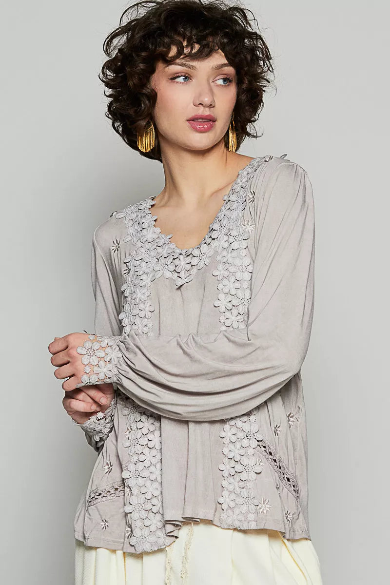 The Floral Embroidery Woven Top offers a relaxed fit and delicate floral lace trim along the low V neckline. Floral embroidery detailing on the side front adds a charming touch to the design. The back features see-through lace shirring below the yoke to provide a roomy fit. This top is elegantly finished with clean hems for a polished look. Complete with shirred long sleeves and scalloped floral trim with a side-button closure, this top exudes feminine charm and sophistication.
