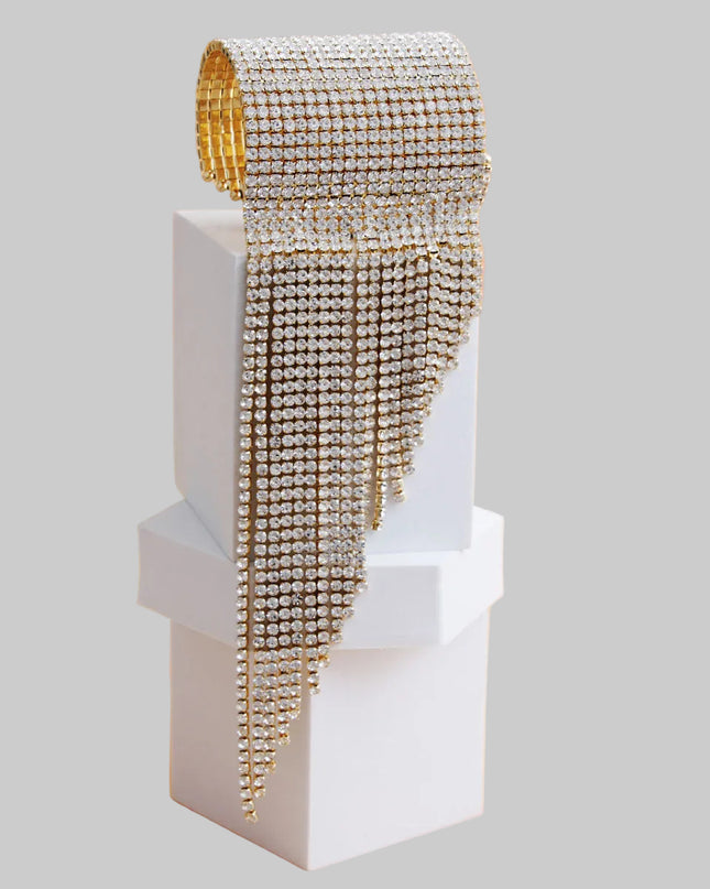A bold gold cuff featuring twenty sleek fringe lines that drape with fluid, eye‑catching movement. Crafted from polished metal in a radiant gold finish, this adjustable statement piece delivers high‑impact shine with a modern, geometric edge. 
