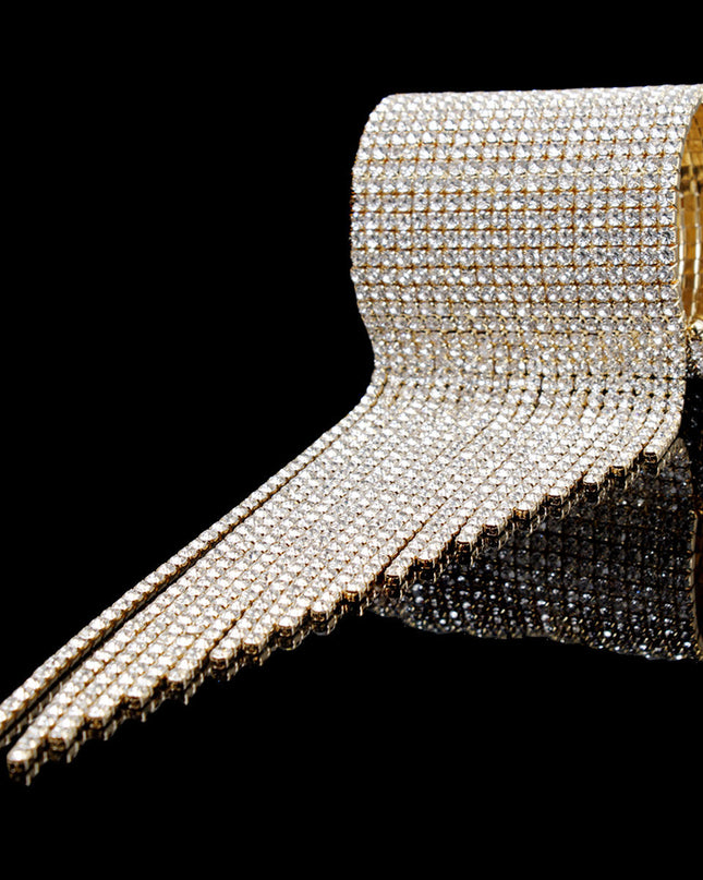 A bold gold cuff featuring twenty sleek fringe lines that drape with fluid, eye‑catching movement. Crafted from polished metal in a radiant gold finish, this adjustable statement piece delivers high‑impact shine with a modern, geometric edge. 
