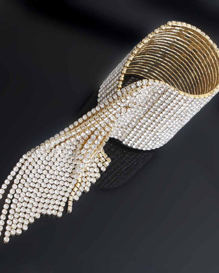 A bold gold cuff featuring twenty sleek fringe lines that drape with fluid, eye‑catching movement. Crafted from polished metal in a radiant gold finish, this adjustable statement piece delivers high‑impact shine with a modern, geometric edge. 