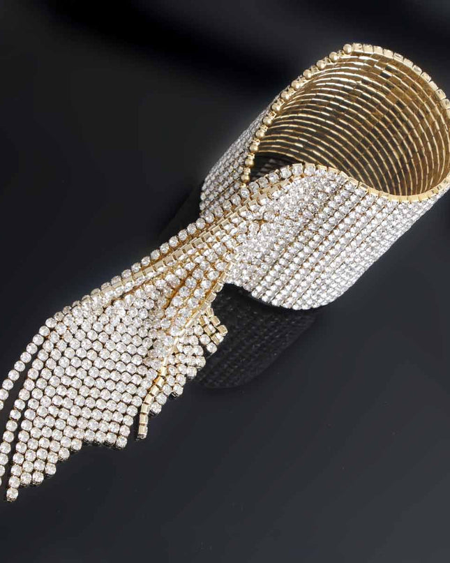 A bold gold cuff featuring twenty sleek fringe lines that drape with fluid, eye‑catching movement. Crafted from polished metal in a radiant gold finish, this adjustable statement piece delivers high‑impact shine with a modern, geometric edge. 