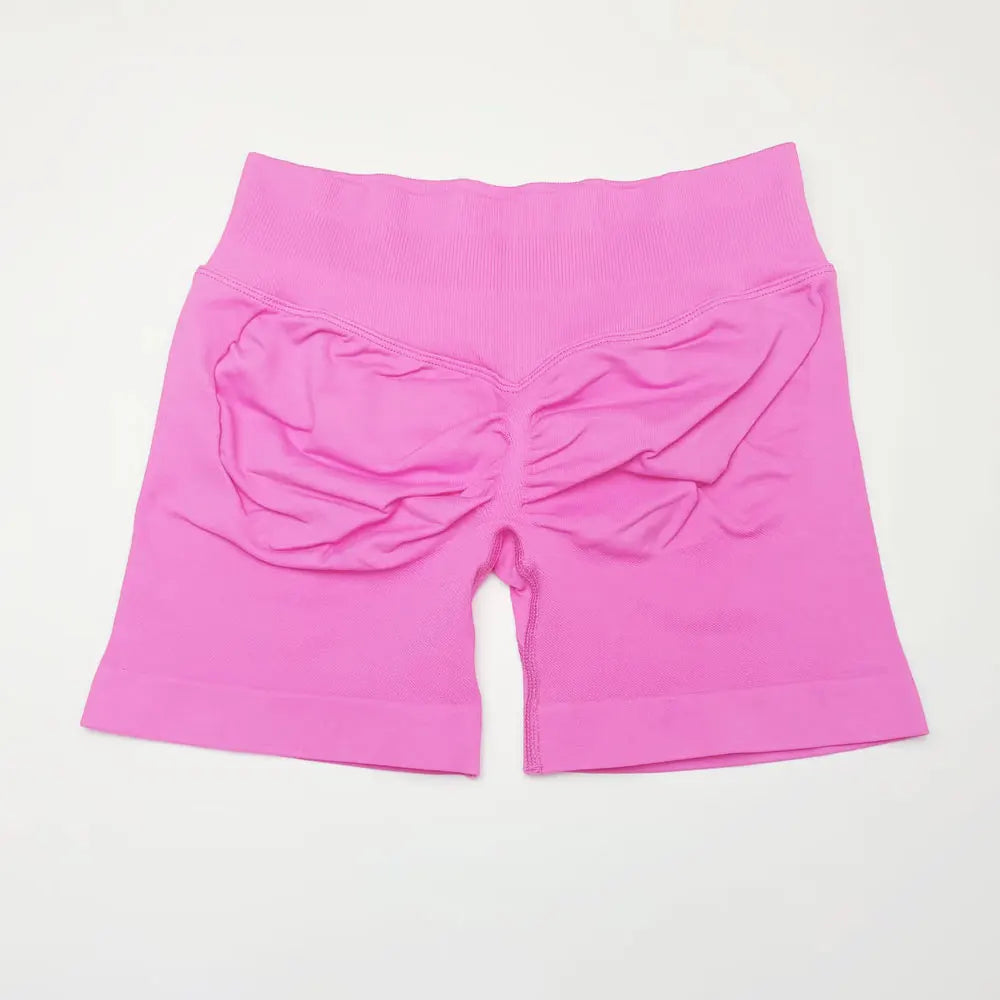 She's wearing pink high-waisted seamless 4.5" gym shorts and a black top.