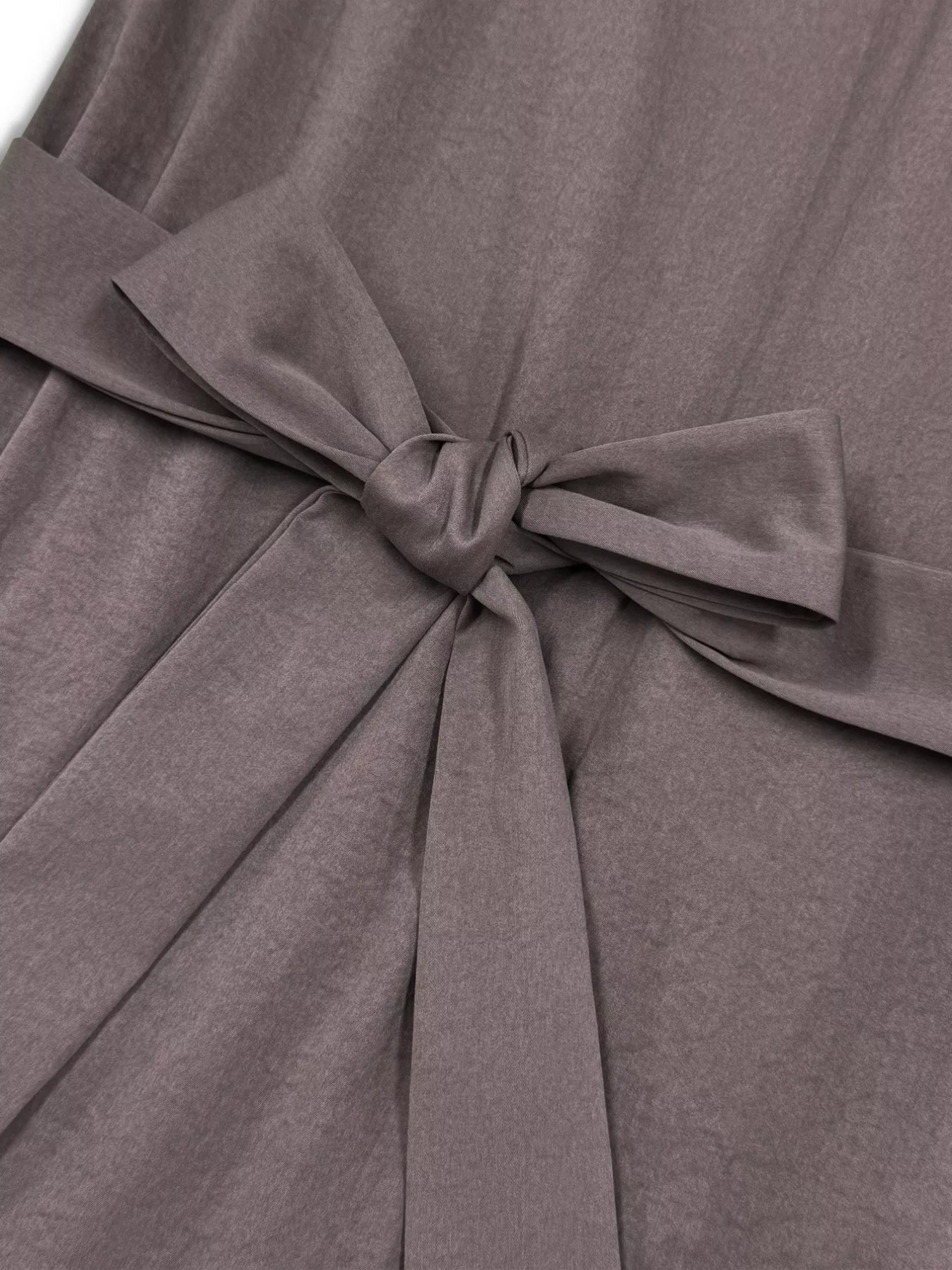 Close-up of a brown, gray dress with a tied bow detail.