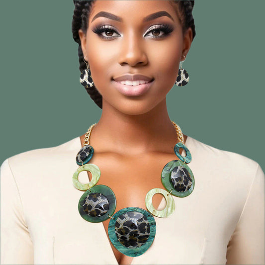 Women's Link Necklace Set Trending Marbled Shades of Green Acrylic with Glitter Linked Collar Design Featuring Rounded Leopard Print Acrylic Discs Details. Center Disc measures 2.75". Gold Metal Chain Lobster Clasp Closure. Includes Matching Fishhook Earrings.