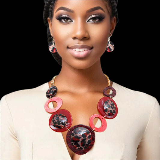 Women's Link Necklace Set Trending Marbled Shades of Red Acrylic with Glitter Linked Collar Design Featuring Rounded Leopard Print Acrylic Discs Details. Center Disc measures 2.75". Gold Metal Chain Lobster Clasp Closure. Includes Matching Fishhook Earrings.