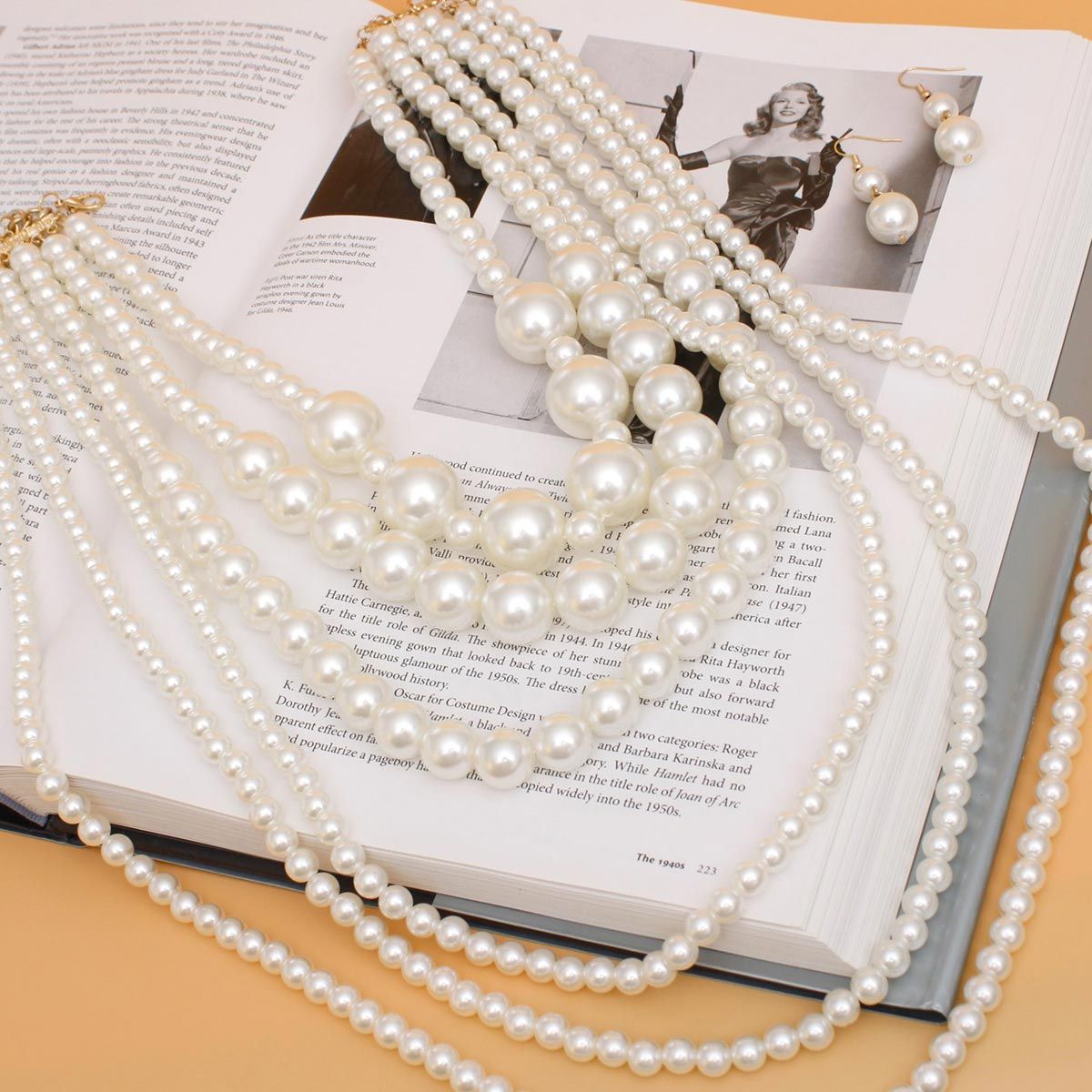 Women's Pearl Necklace Set 6 Strand Acrylic Cream Pearl Long Layered Necklace Featuring Bubblegum Pearl Center Details. Necklace Layers Measure 20" to 36". Gold Metal Lobster Clasp Closure. Includes Matching Fishhook Double Drop Pearl Earrings.