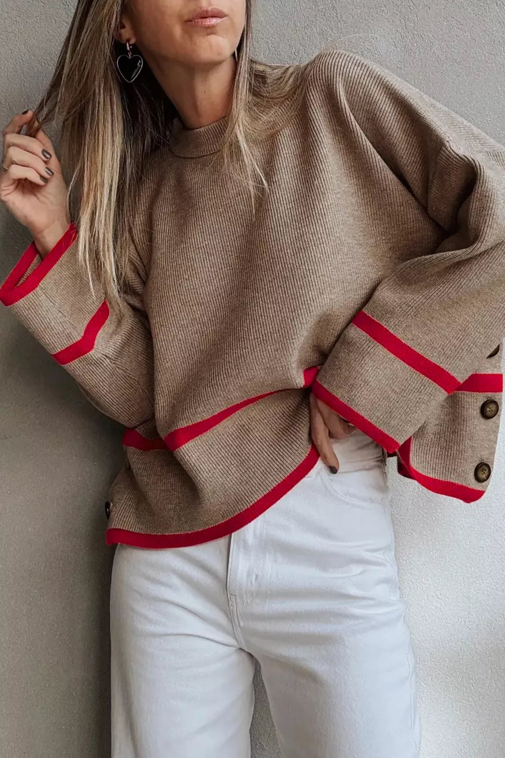 Brown sweater with red accents and white pants 