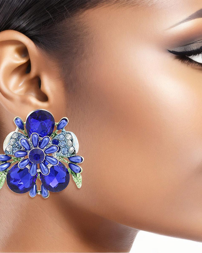 Women's Clip-On Earrings. Silver Metal Flower Clip-Ons Featuring Royal Blue Teardrop Crystals, Rhinestones, Oval Pearls, and Green Leaf Details. Paddle-back Clip-Ons.