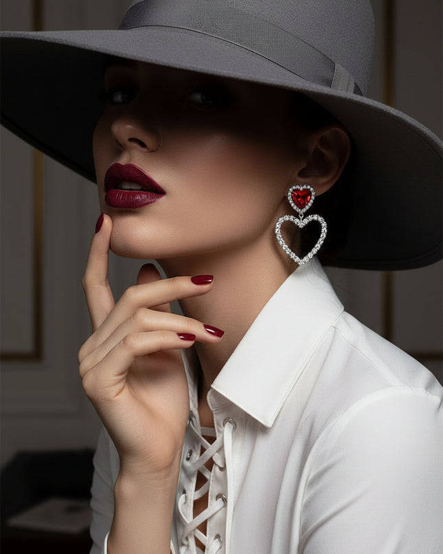A radiant pair of silver‑tone heart earrings accented with bold red crystal inlays and delicate cutout detailing. 