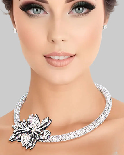 A silver choker necklace with a double pointed flower rhinestone detail and a matching set of earrings.