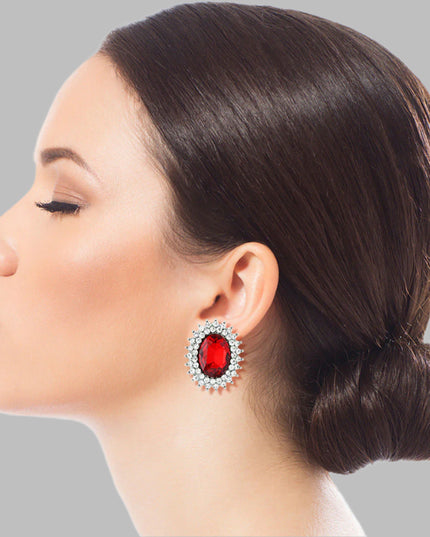 Silver Metal Oval Stud Earrings Featuring Red Crystal with Rhinestone Trim. Earrings measure .85 inches wide