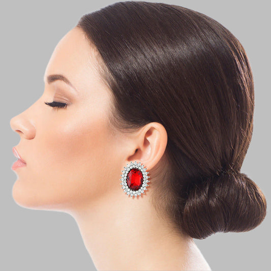 Silver Metal Oval Stud Earrings Featuring Red Crystal with Rhinestone Trim. Earrings measure .85 inches wide