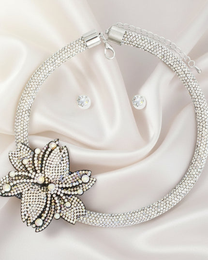 A silver choker necklace with a double pointed flower rhinestone detail and a matching set of earrings.