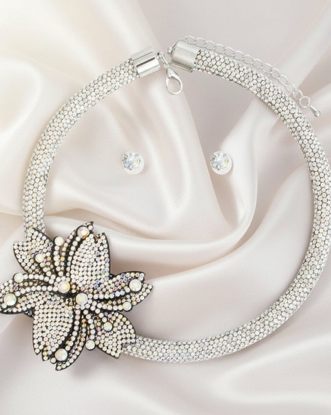 A silver choker necklace with a double pointed flower rhinestone detail and a matching set of earrings.